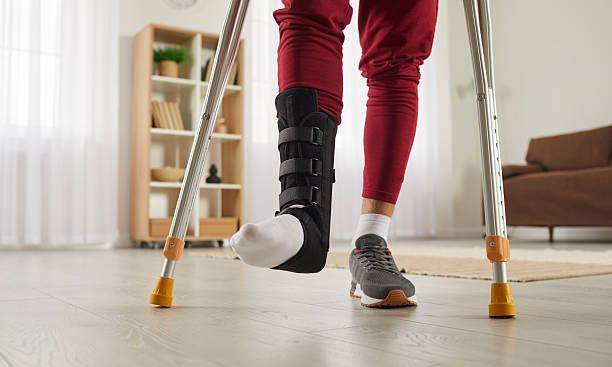 Man walking with crutches wearing an ankle support brace during recovery from ankle surgery